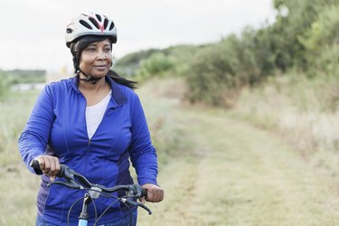 Black woman riding bike in park with helmet